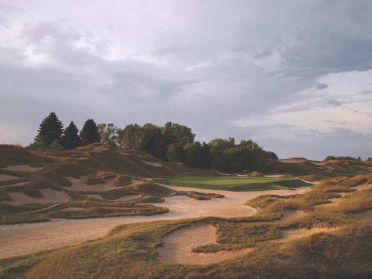 Large sand bunkers lead to raised golf green