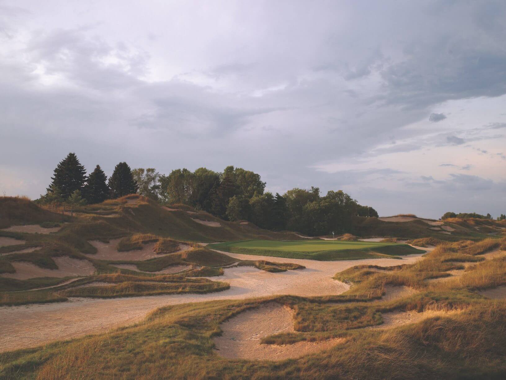 Large sand bunkers lead to raised golf green