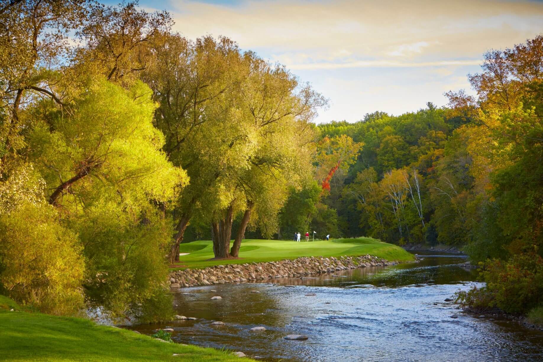 Fall trees cast golden light over a golf course
