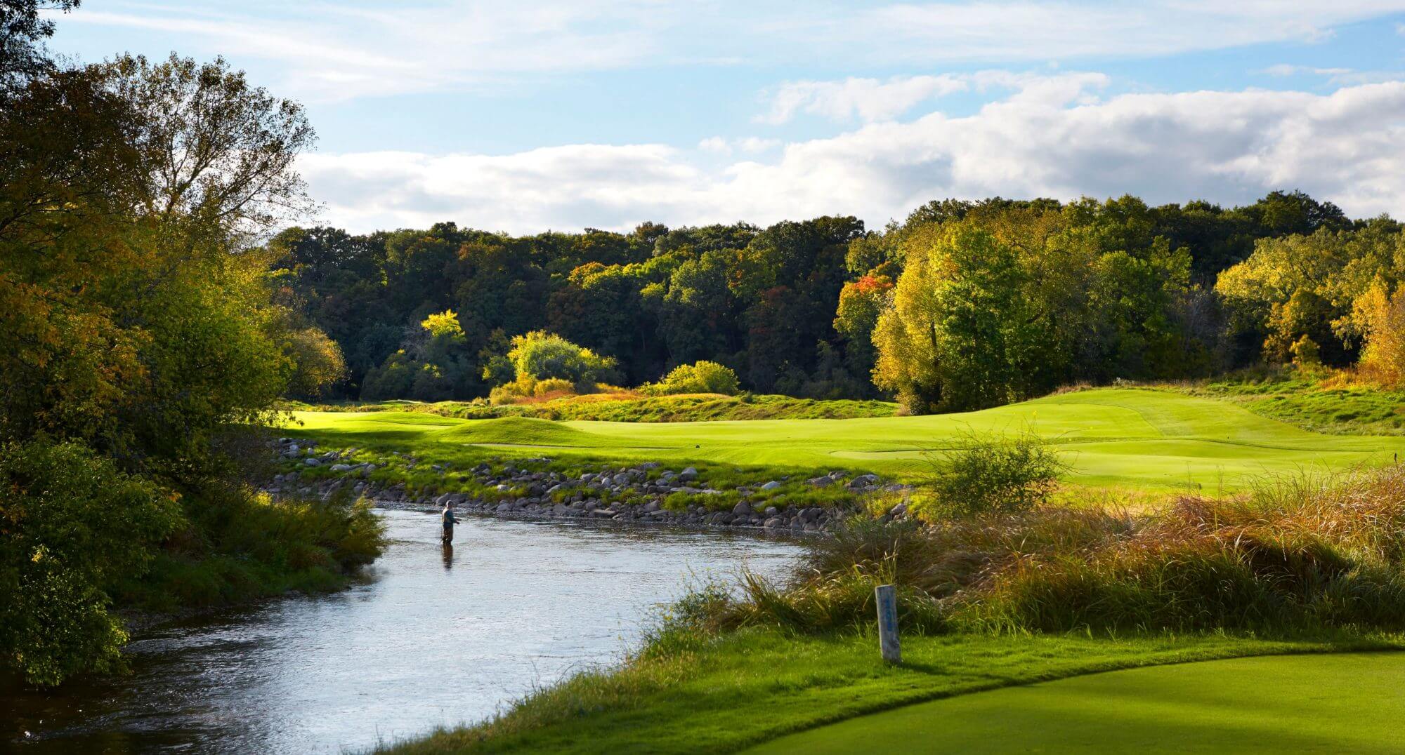 Man fishes in river next to golf course