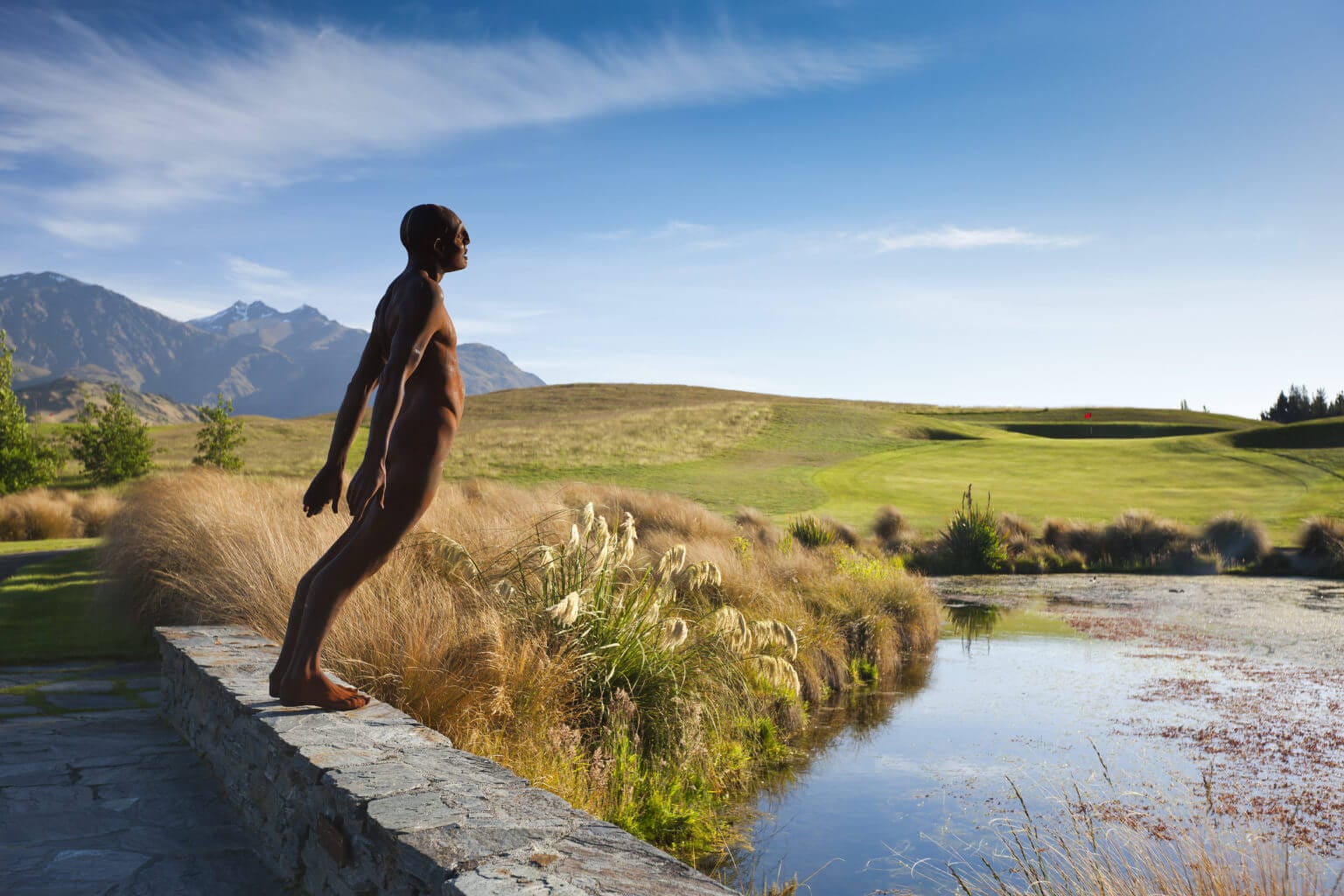 Bridge with sculpture of male leaning toward a lake