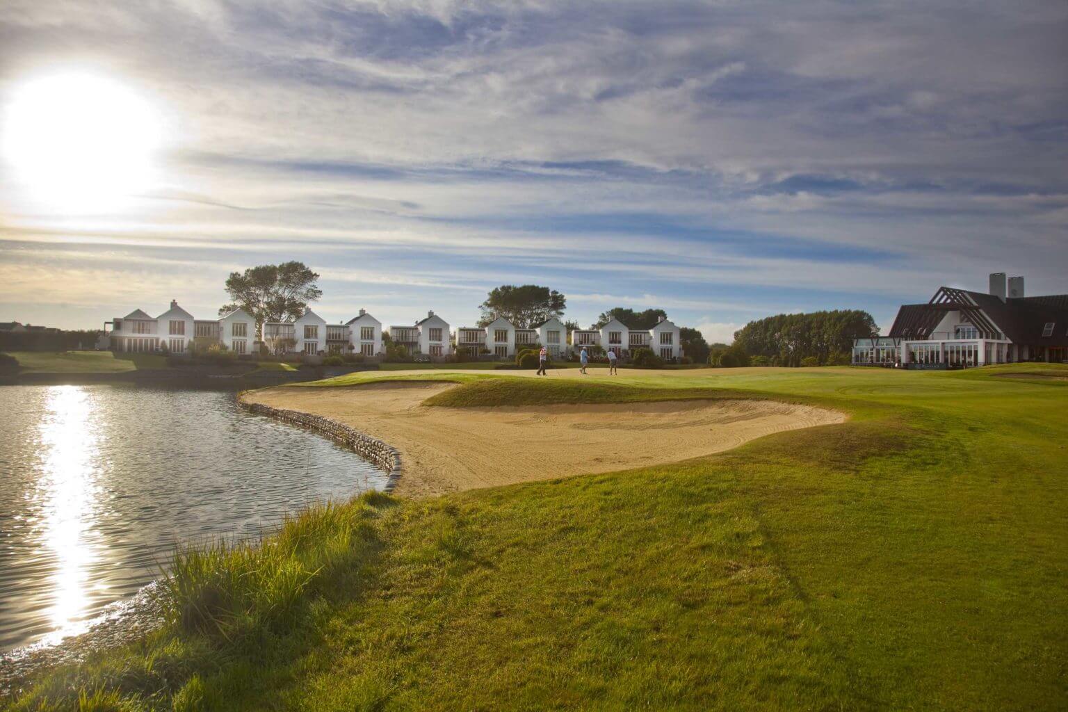 Large bunker and lake protect a raised golf green