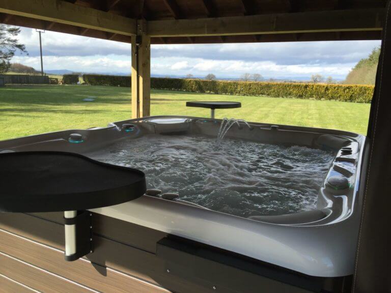 Outdoor hot tub overlooks lush paddock