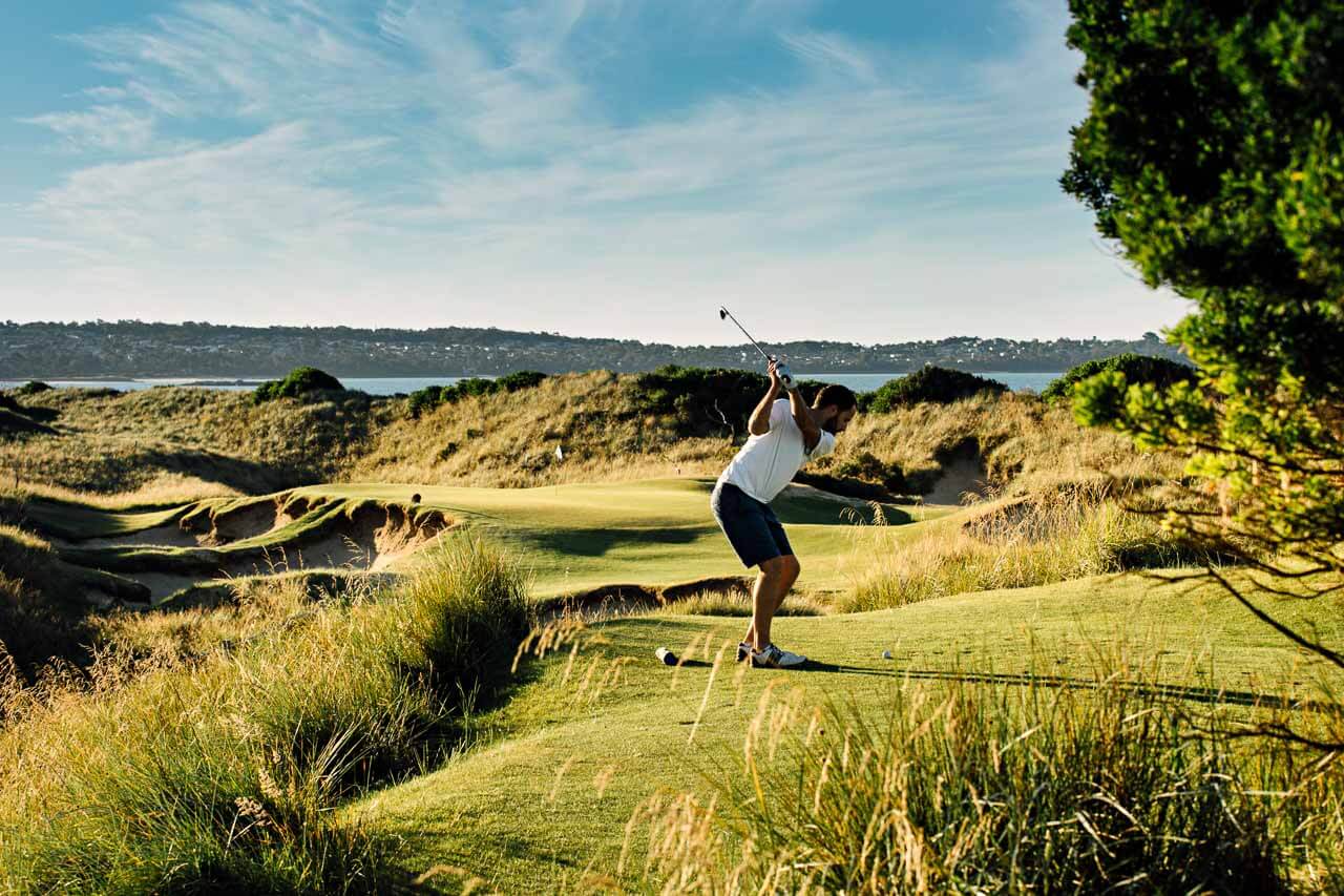 Man tees off on a par-3 hole at Barnbougle Dunes golf course