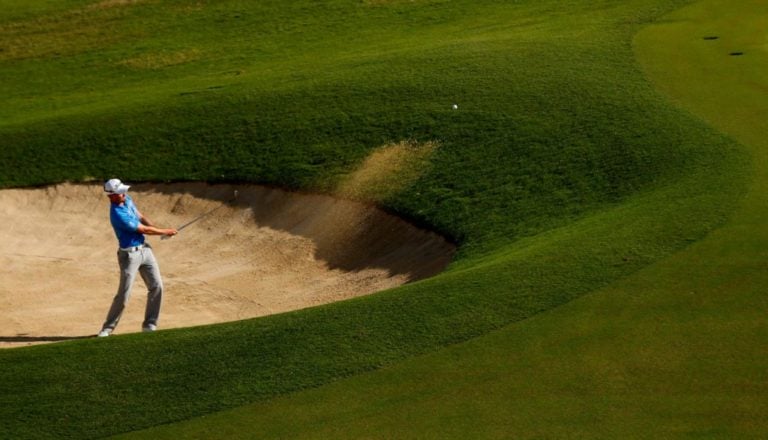 Golfer playing out of bunker at Fiji International golf tournament