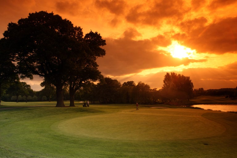 Contrasting orange sky with green golf course, The Belfry Resort, England