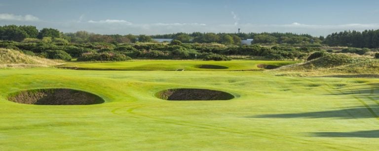 Looking down a fairway at the green, littered with deep bunkers at Dundonald Links, Scotland, United Kingdom
