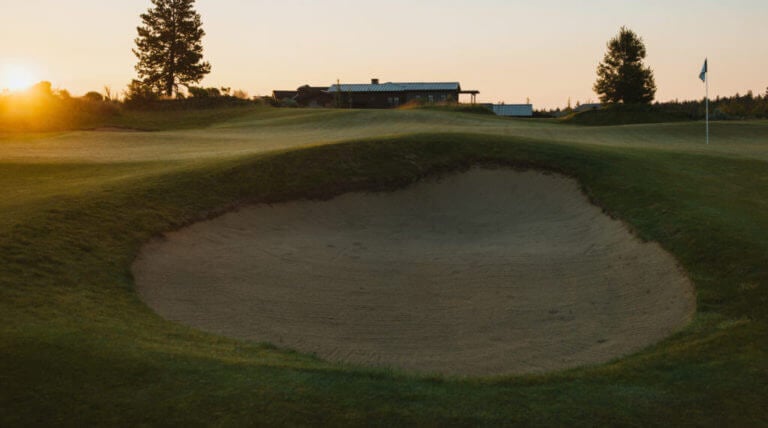 Image of a wide bunker and distant building on the golf course at Tetherow Resort, Bend, Oregon, USA