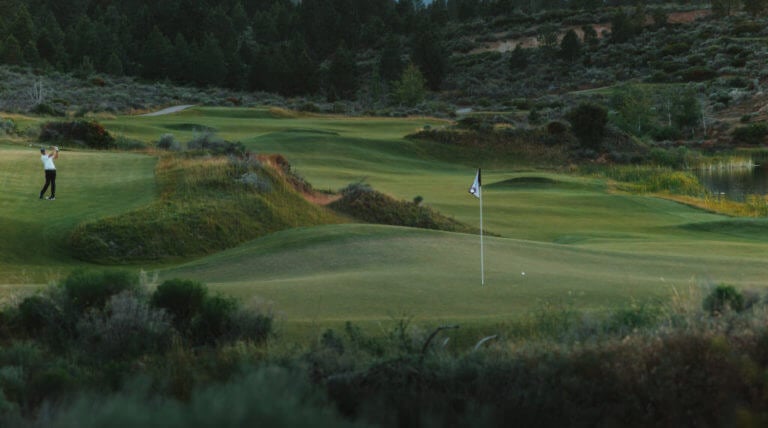 Image of a golfer playing a shot at the green on the golf course at Tetherow Resort, Bend, Oregon, USA