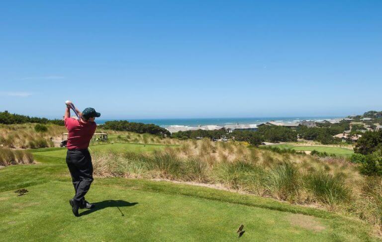 Image of a golfer teeing off at the 15th hole of the golf course, Salishan Resort, Oregon, USA