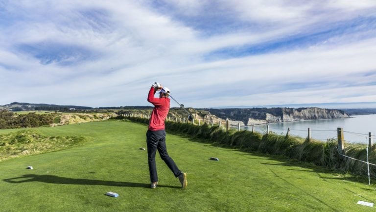 A golf player tees off at Cape Kidnappers, Hawke's Bay, New Zealand