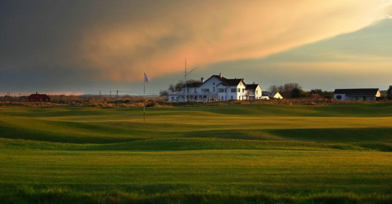 Image of the 2nd green in front of the clubhouse at Royal Cinque Ports Golf Club, Kent, England