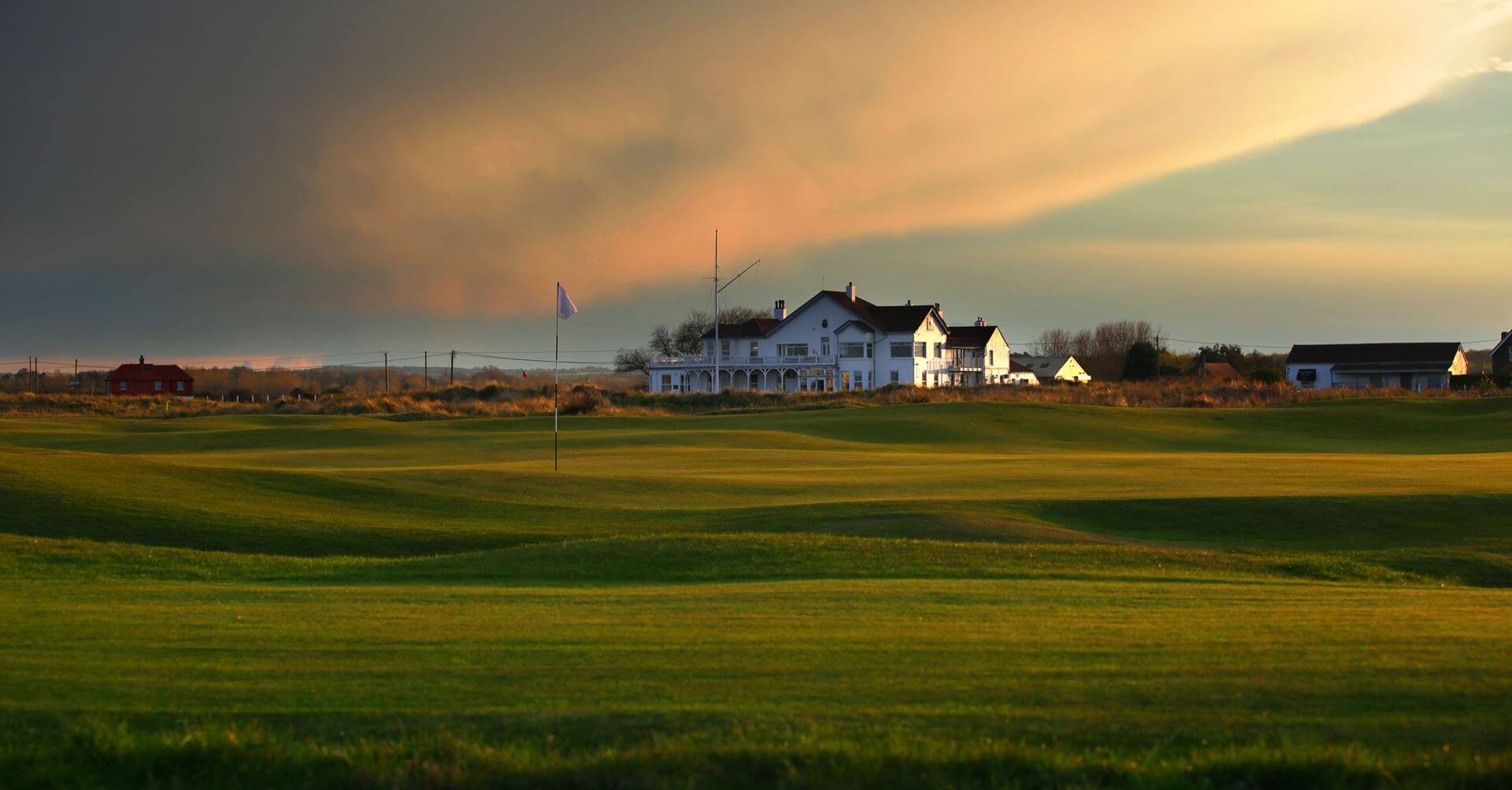 Image of the 2nd green in front of the clubhouse at Royal Cinque Ports Golf Club, Kent, England