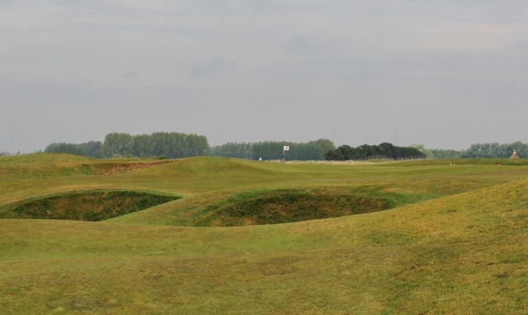 Image overlooking a fairway with pot bunkers and the flag of St George on the horizon, Royal St. George's Golf Course, Kent, England
