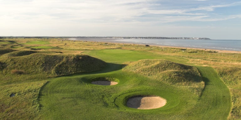 Aerial image of bunkers and knolls next to the ocean at Royal St. George's Golf Course, Kent, England