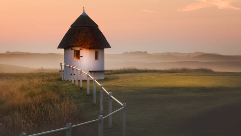 Image a white fence bordering the first tee and the starter hut at Royal St. George's Golf Course, Kent, England