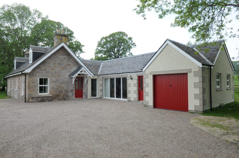 Image of the stone Castle Cottage with red doors at Castle Stuart Golf Links, Inverness, Scotland