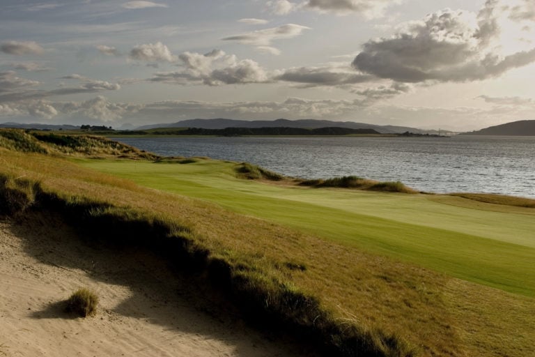 Image of the 2nd hole fairway next to the ocean looking at distant hills at Castle Stuart Golf Links, Inverness, Scotland