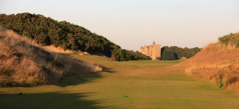 Image looking down the par-3 4th hole with the old castle Stuart in the background at Castle Stuart Golf Links, Inverness, Scotland
