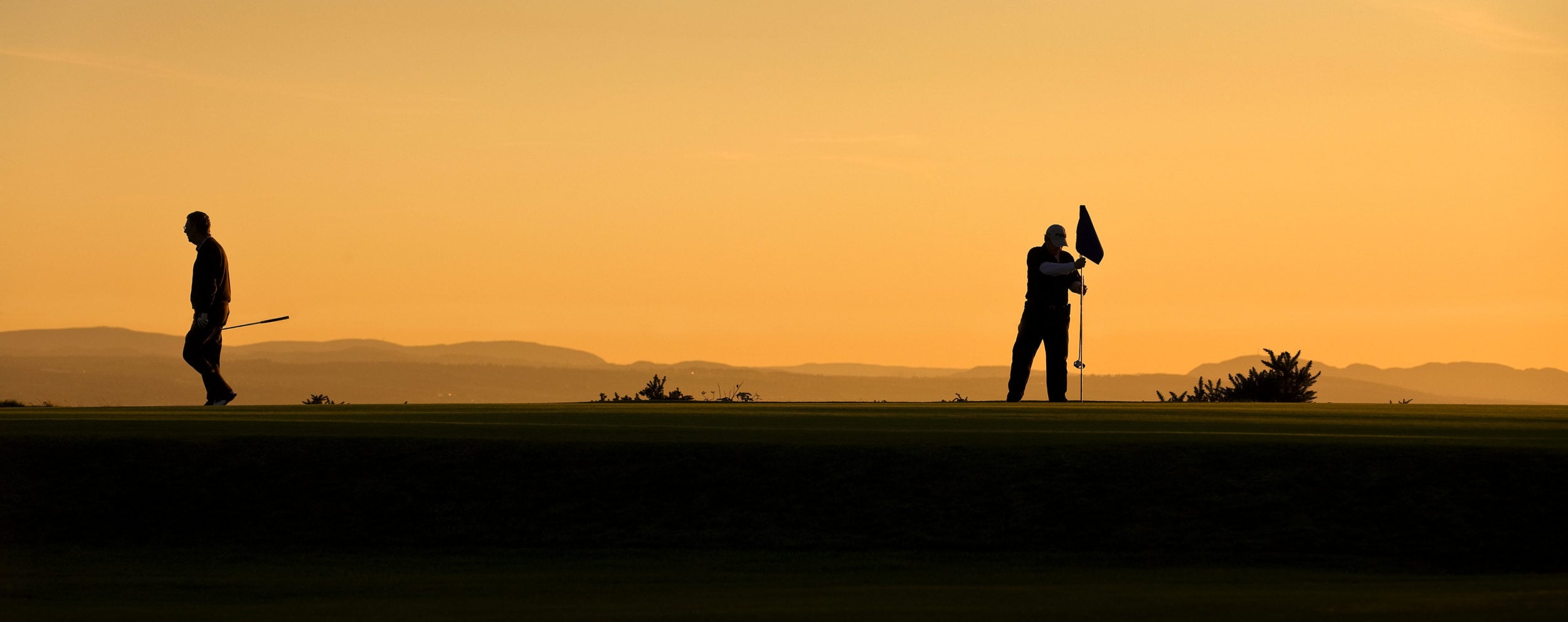 Dusk image of two golfers on the putting green at Fortrose and Rosemarkie golf Links, Inverness, Scotland