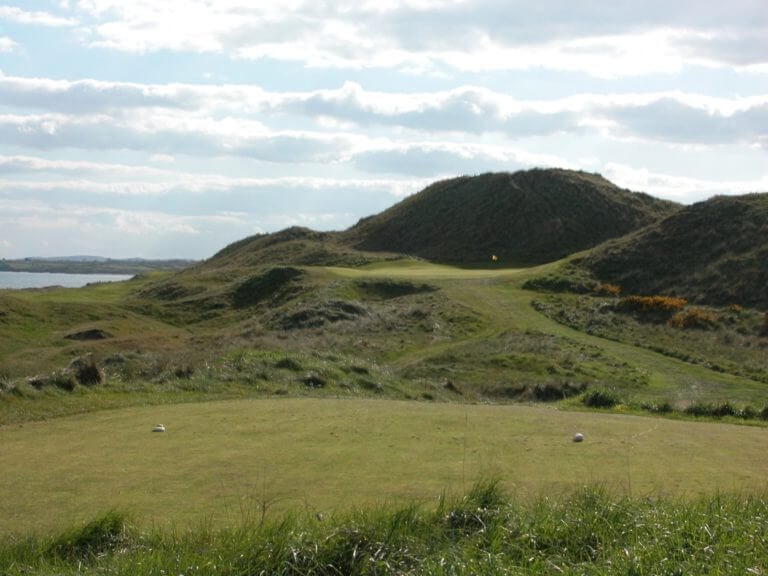 Image depicting the par-3 12th green at the bottom of a large sand dune, The European Golf Club, Ireland