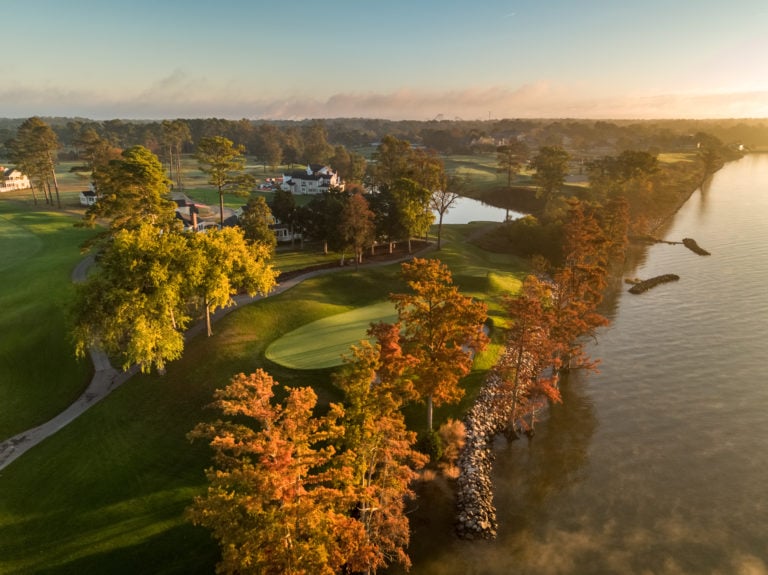 Aerial image depicting the 17th green with autumn leaves bathed in orange light and the James River, Kingsmill Resort, Williamsburg Virginia, USA