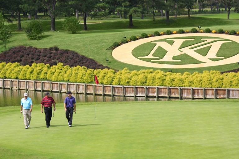 Image depicting three golfers on the 18th green of the River Course with the resort logo in the background, Kingsmill Resort, Williamsburg Virginia, USA