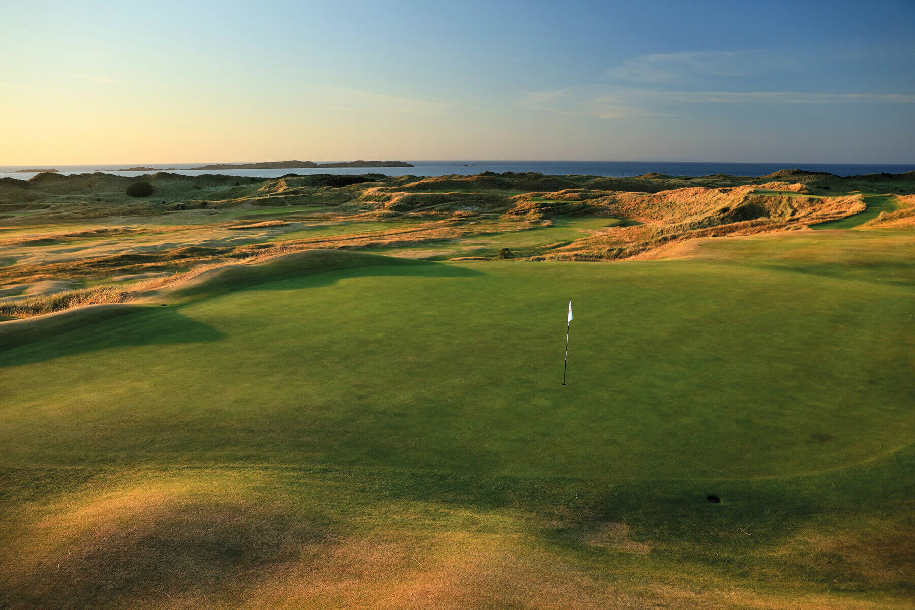 Image depicting the 16th green as the sun sets at Royal Portrush Dunluce Golf Course, Portrush, County Antrim, Northern Ireland