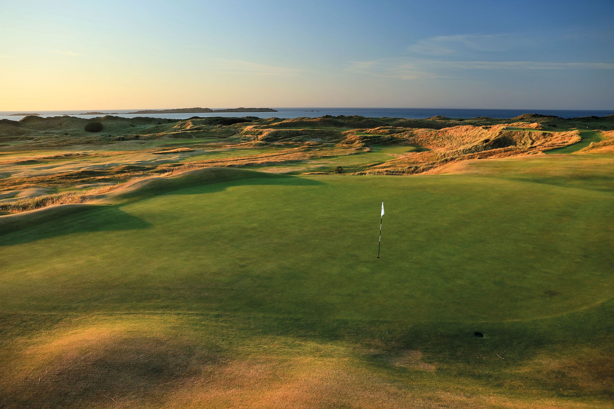 Image depicting the 16th green as the sun sets at Royal Portrush Dunluce Golf Course, Portrush, County Antrim, Northern Ireland