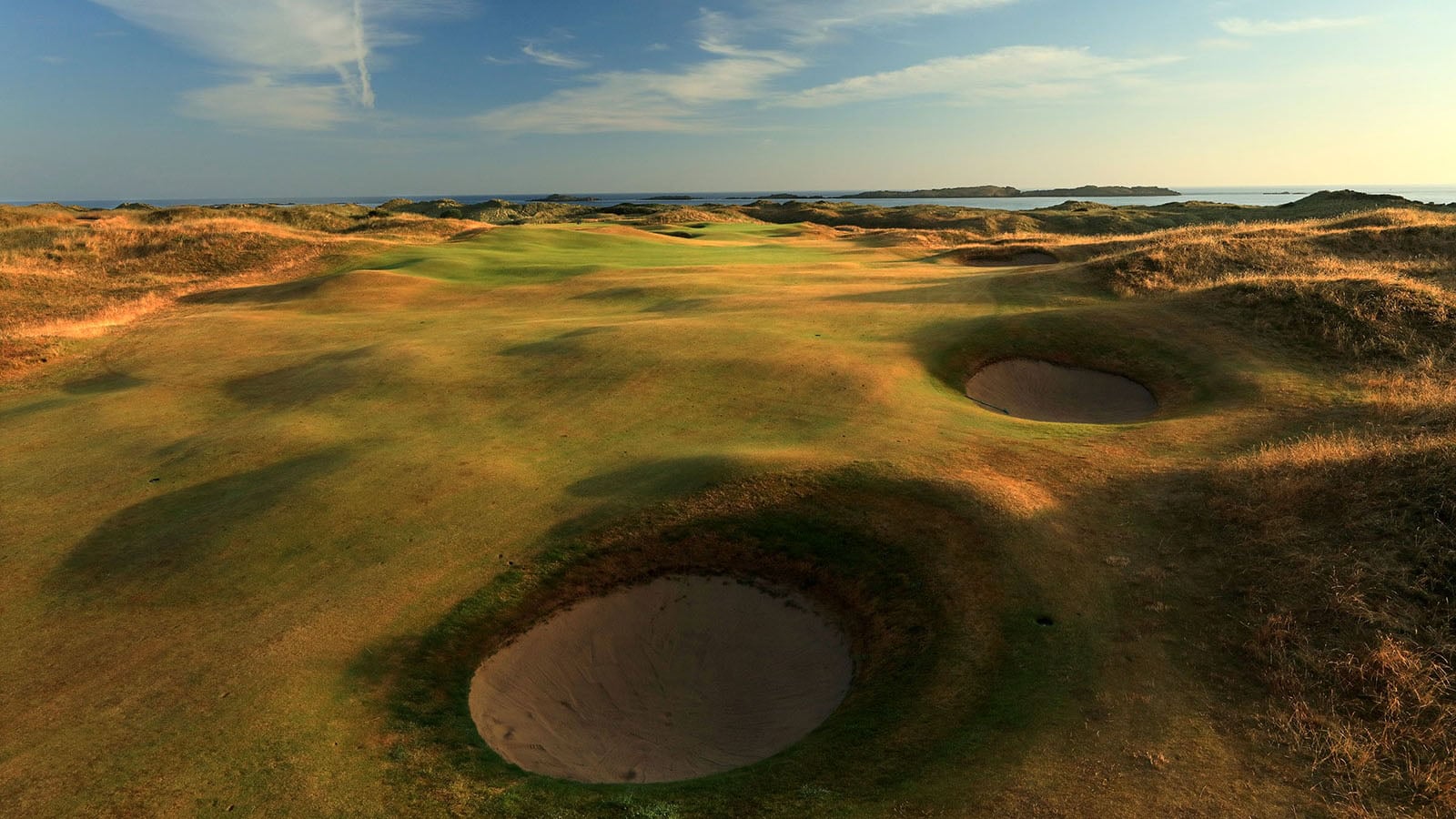 Aerial view of the 2nd green and deep pot bunkers with long shadows at Royal Portrush Dunluce Golf Course, Portrush, County Antrim, Northern Ireland