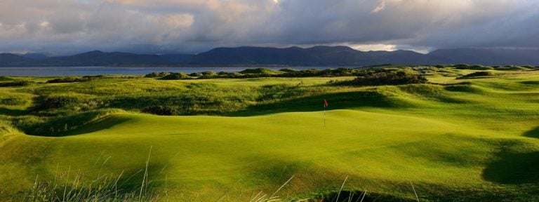 Image of a green in the foreground and clouds hanging over distant mountain tops, Dooks Golf Club, County Kerry, Ireland