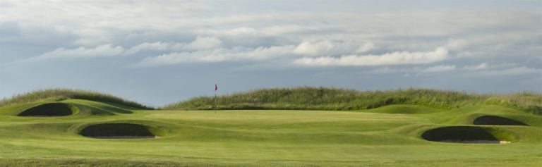 Landscape image of a raised green surrounded by pot bunkers on Gullane No.1 Golf Course, East Lothian, Scotland