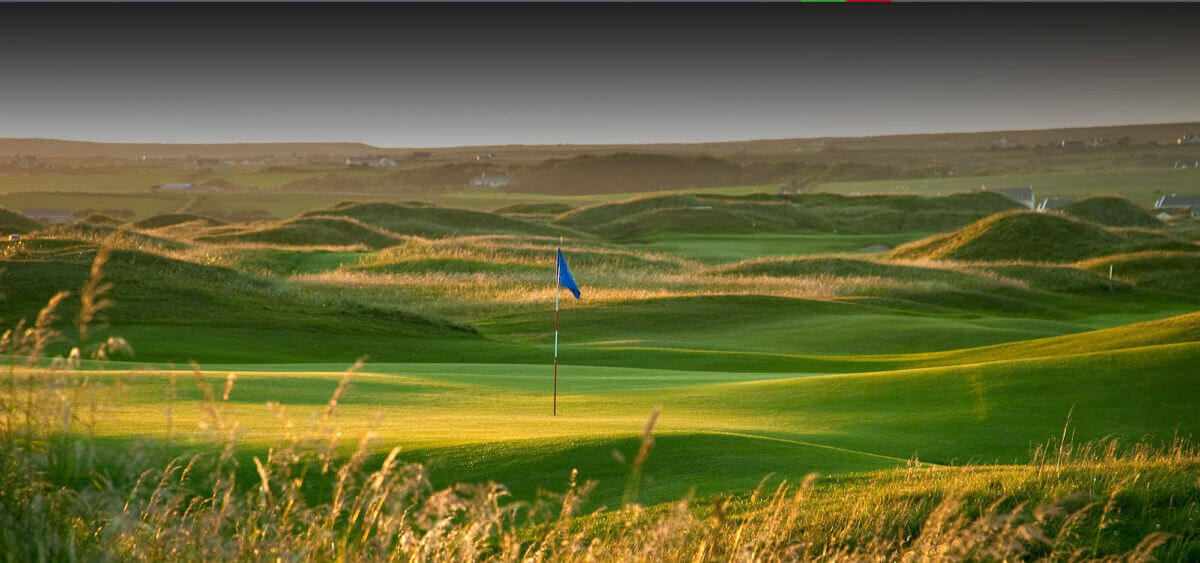 Image displaying the 3rd hole with blue flag sticking out on the Castle Golf Course at Lahinch Golf Club, County Clare, Ireland
