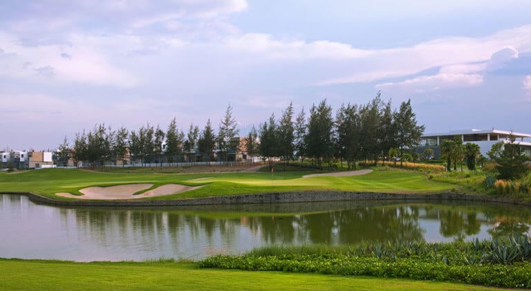 Image overlooking the 9th hole approach shot from the tee over a lake to the green, Montgomerie Links Vietnam Golf Course, Da Nang, Vietnam, Asia