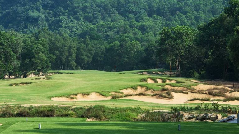 Image overlooking a tee box and the approach to a distant uphill green,Laguna Lang Co Golf Club, Da Nang, Vietnam