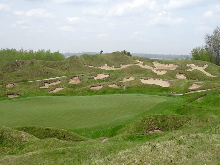 Image of the 13th green surrounded by raised hills and littered with bunkers on The Irish Golf Course, Whistling Straits, Destination Kohler, Sheboygan, Wisconsin, USA