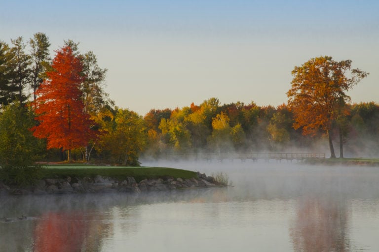 Mist rises off a lake near the thirteenth green at Sentryworld Golf Club
