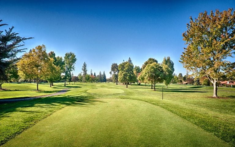 An open fairway is flanked by spread-out trees at Silverado Golf Resort