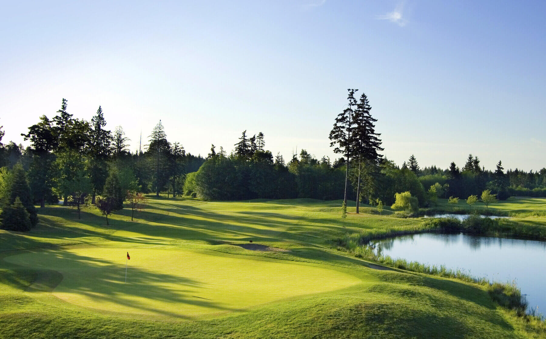 The thirteenth hole is flanked by a lake on one side and trees on the other