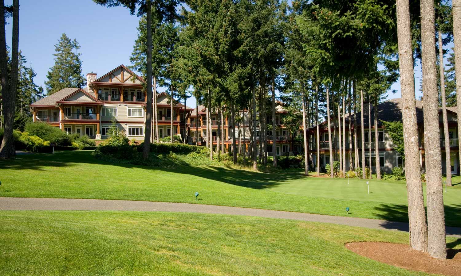 External view of practice putting green and resort buildings through trees