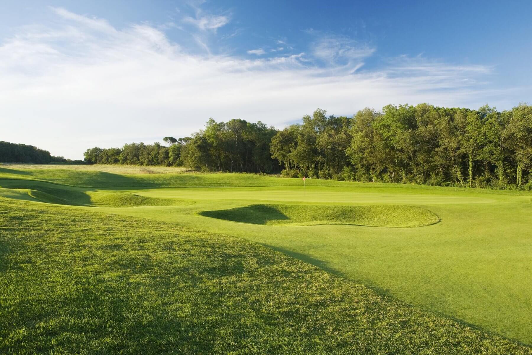 The fourteenth hole at PGA Catalunya golf course is flanked by grass-filled bunkers