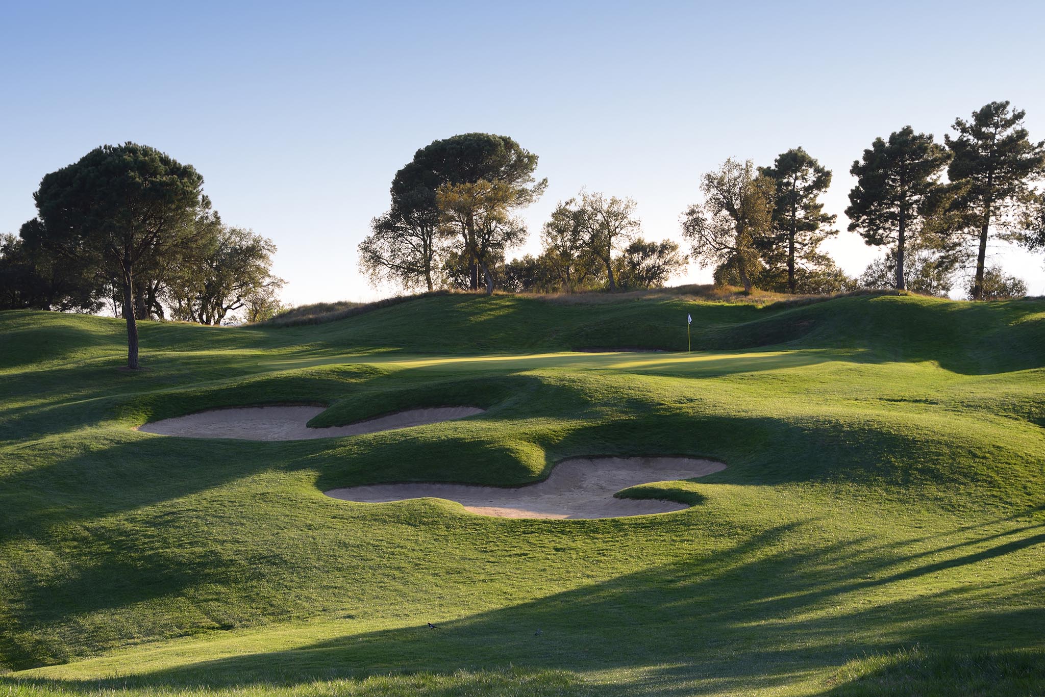 A raised sixteenth green is protected by large odd-shaped bunkers
