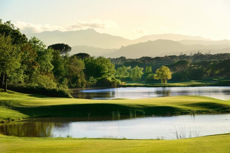 A green is flanked on three sides by a lake on the Tour Course at PGA Catalunya