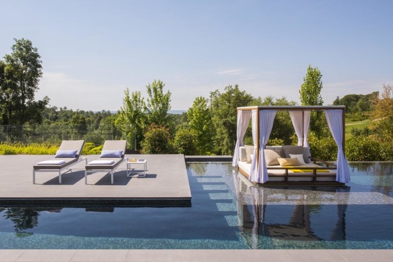 A pool cabana and outdoor reclining chairs await guests at the PGA Catalunya Resort