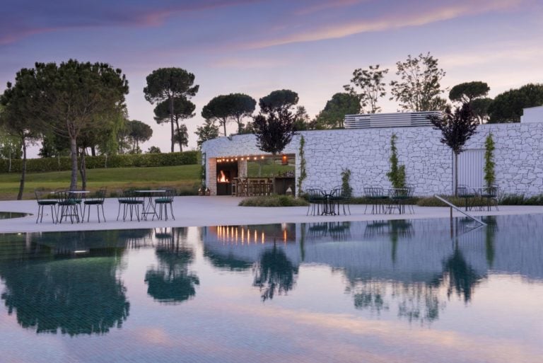 Dusk settles over a still pool and outside dining area at PGA Catalunya Resort