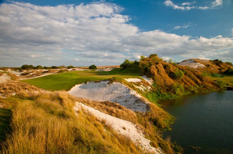 A large raised green leads to a cliff and lake below on the Red Golf Course at Streamsong Resort