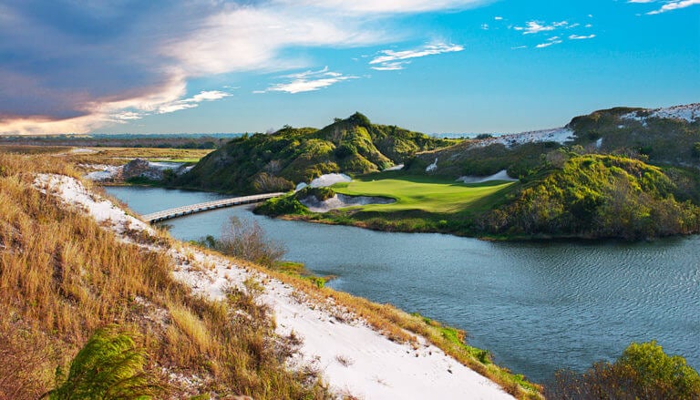 Golfers must hit over a lake on the Blue course seventh hole at Streamsong Resort in Florida