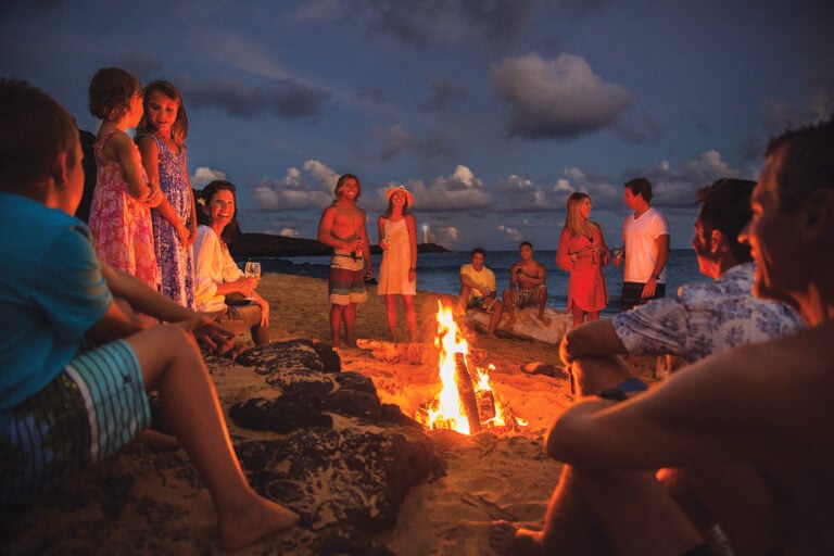 Resort guests enjoy a communal social fire on the beach at Timbers Resort in Hawaii