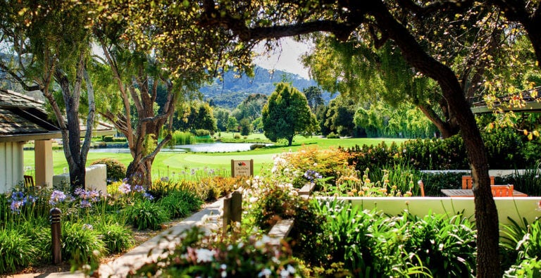 View through a garden to the golf course on a sunny day at Quail Lodge Golf Course in California