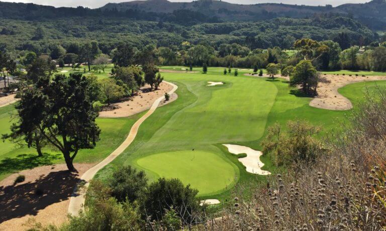 Aerial view of an open fairway and green surrounded by sand bunkers at Quail Lodge Golf Course in California